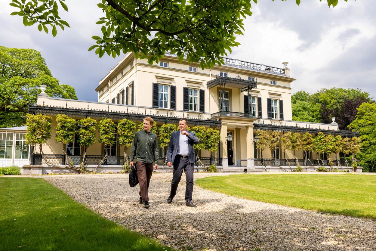 Kool leidt Geels rondt over het groene terrein van landgoed Bronbeek