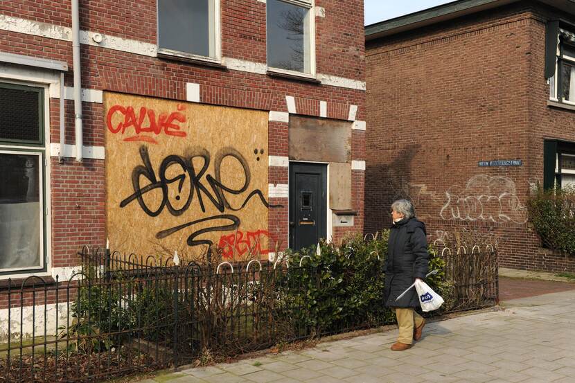 Vrouw loopt langs leegstaand pand