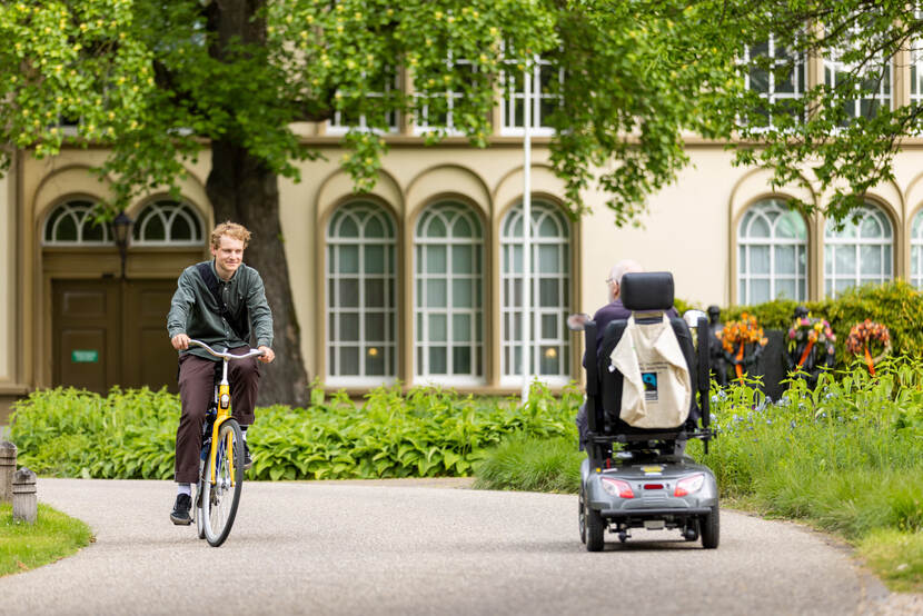 Geels fietst het terrein af terwijl een veteraan in een scootmobiel tegemoet rijdt