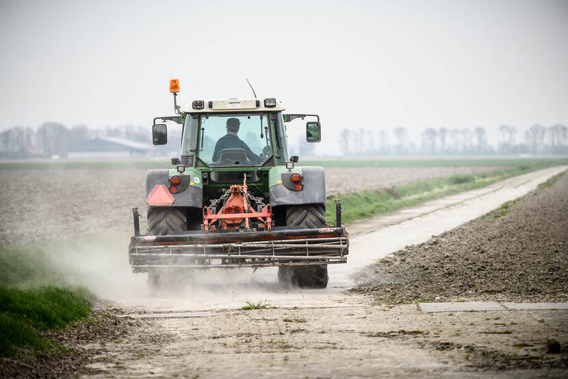 Tractor rijdt over landbouwgrond