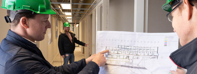 Twee mannen met bouwhelmen bekijken een bouwtekening, foto: Bas Kijzers